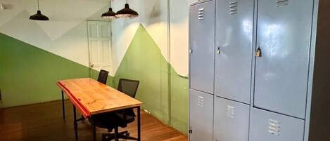Un salón de conferencias con una mesa de madera, sillas y un archivador metálico grande.