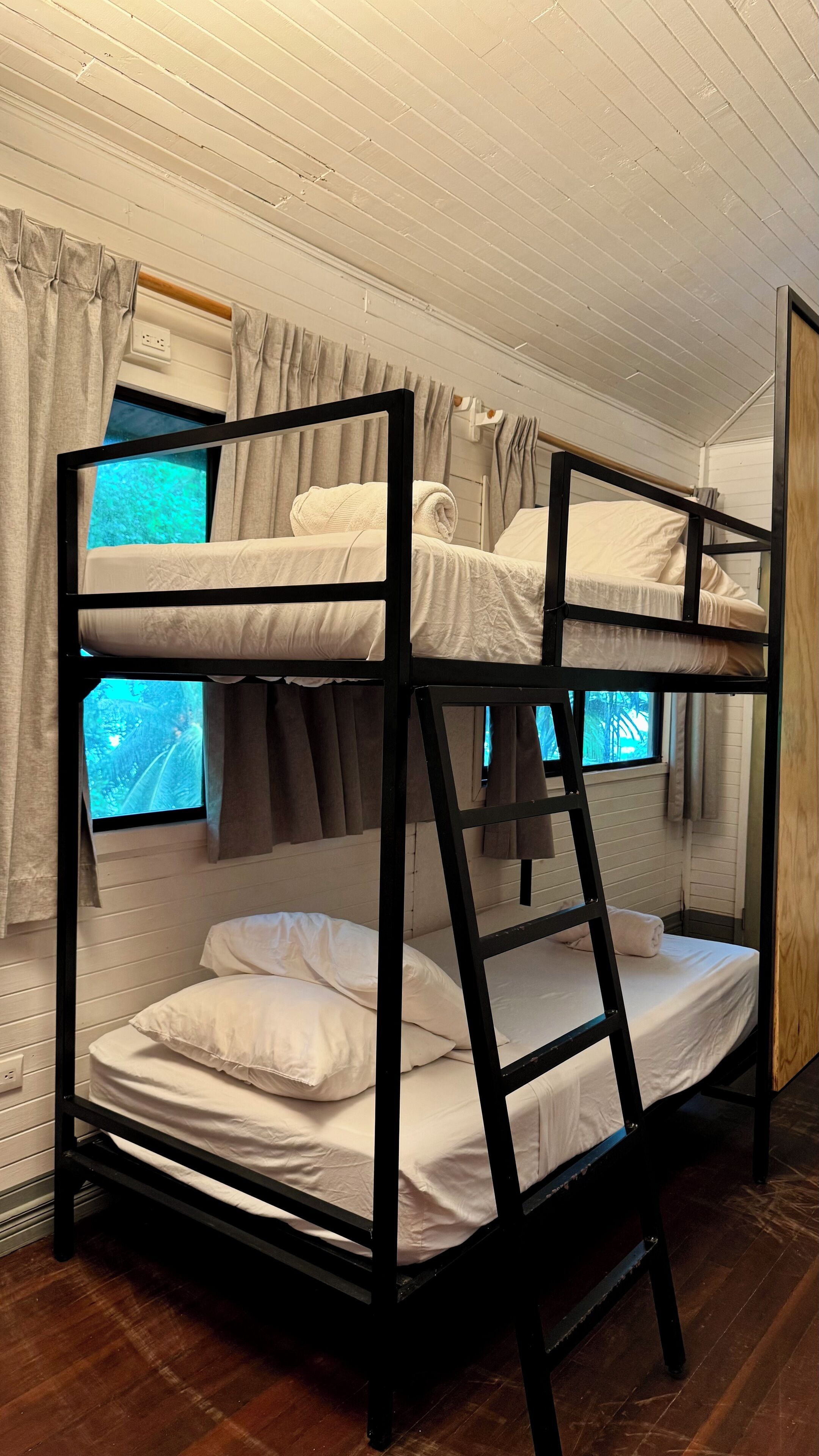 Een slaapkamer met een stapelbed, raam en gordijnen.