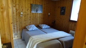 A wooden-paneled room with two beds, a painting of a bear, and a window.