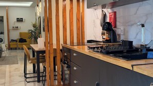 A modern kitchen with a wooden partition, a coffee machine, and a marble backsplash.