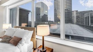 Une chambre d’hôtel dotée d’une grande fenêtre donnant sur des immeubles imposants.