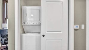 Une buanderie équipée d’un lave-linge et d’un sèche-linge, avec une porte et un interrupteur sur le mur.