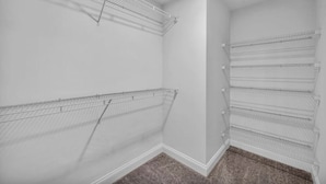 Un placard d’angle doté d’étagères en fil métallique et d’un revêtement de sol en moquette.