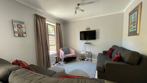 Un salon avec deux canapés, une petite table, un téléviseur et un ventilateur de plafond.