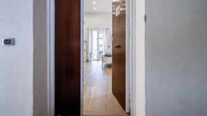 A hallway with a wooden door, a light switch, and a view into a room with a bed and a window. - CasaRÉ - One Bedroom Guest House, Sleeps 2 (Naples)