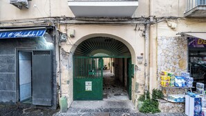 A narrow alleyway with a green gate, a stone wall, and a shop selling toilet paper. - CasaRÉ - One Bedroom Guest House, Sleeps 2 (Naples)