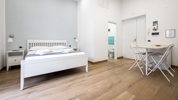 A bedroom with a bed, bedside table, and a desk with chairs. - CasaRÉ - One Bedroom Guest House, Sleeps 2 (Naples)