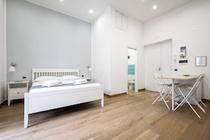 A bedroom with a bed, bedside table, and a desk with chairs.