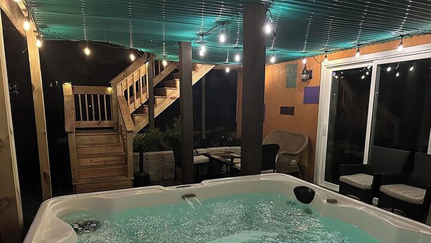 Un jacuzzi con una terraza de madera y escaleras que llevan a un balcón.