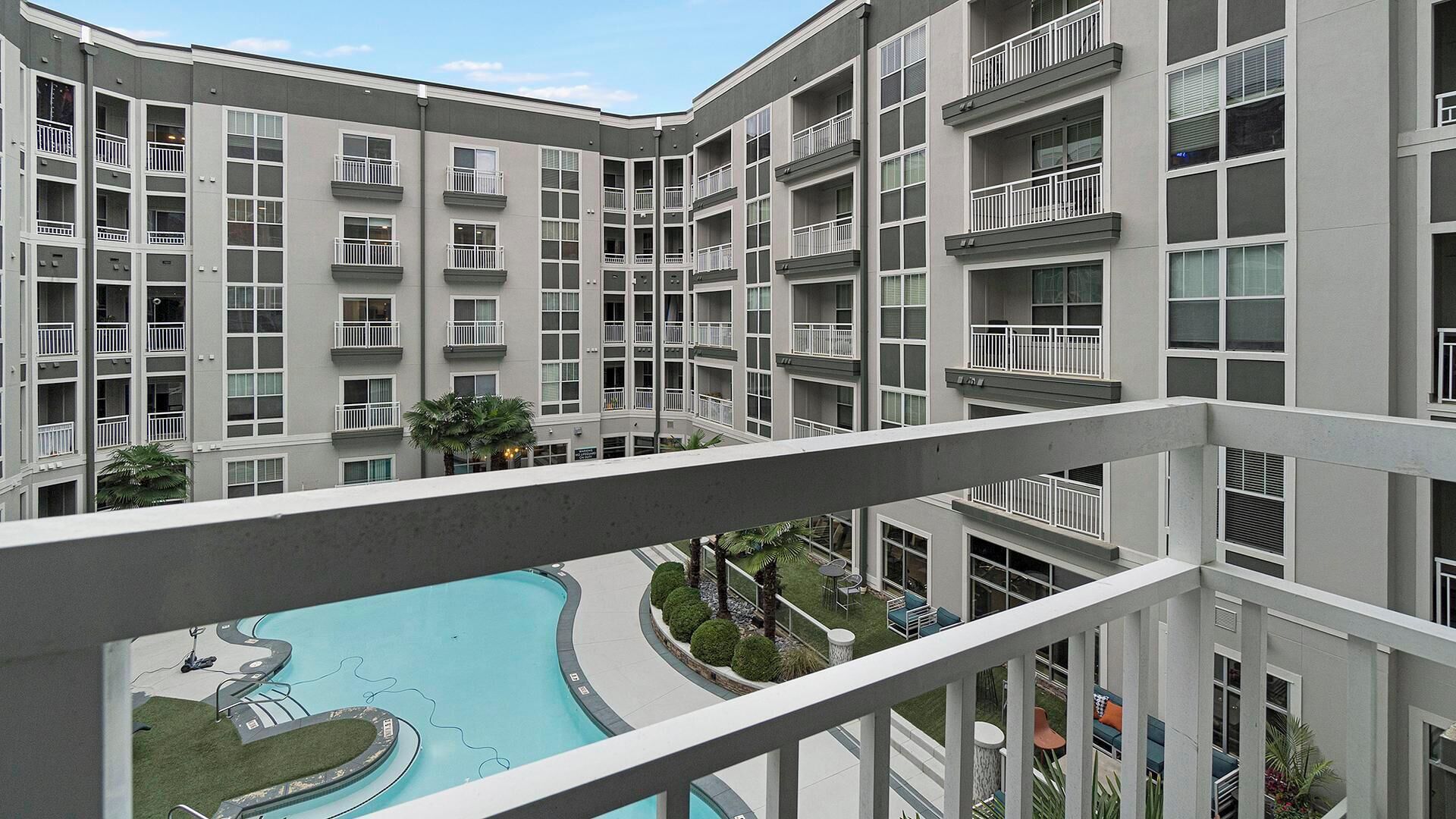 Um edifício residencial de vários andares com varandas, piscina e um pátio ajardinado.