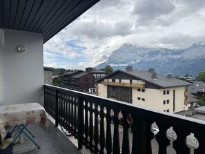Un balcon offrant une vue sur des maisons de montagne et un ciel nuageux.