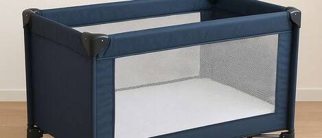 Un corralito portátil para bebés con un panel de malla lateral y un panel frontal sólido, de color azul oscuro y detalles en negro.