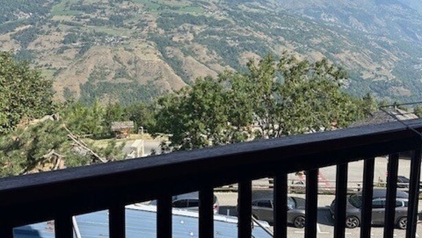 Paisaje montañoso con vista a un estacionamiento y un edificio en primer plano.