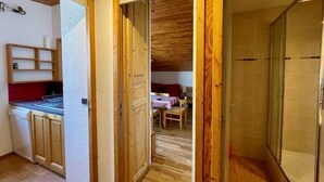 Una cocina compacta con armarios de madera y una estufa integrada, un comedor con mesa y sillas, y un área de ducha con puerta de vidrio.