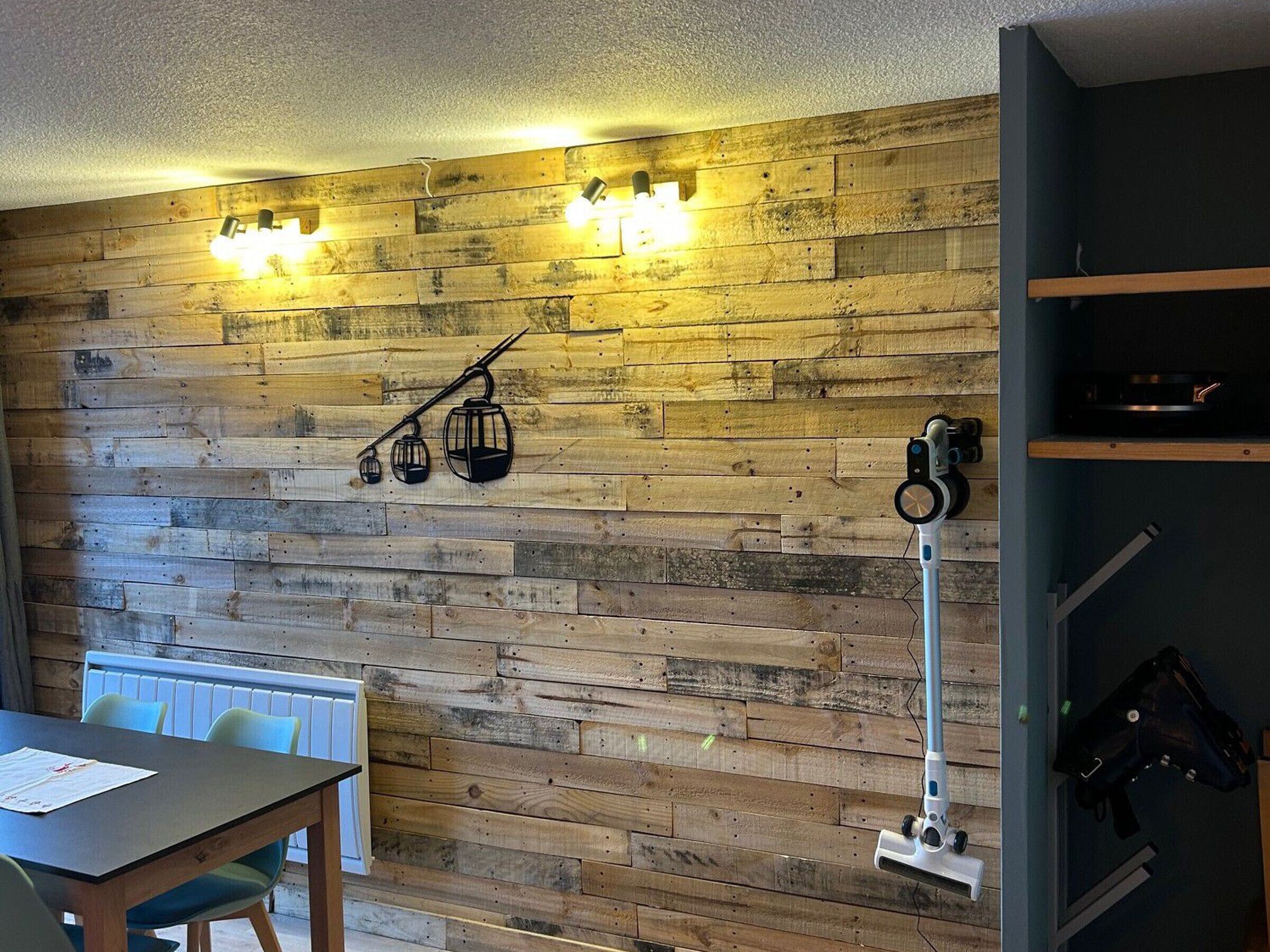 Une pièce avec un mur en bois, une table avec des chaises et un radiateur.