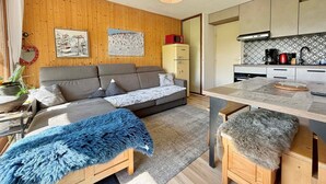 A cozy living area with a sofa, a dining table, and a kitchen area with cabinets and appliances.
