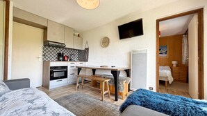 A compact room with a bed, a desk, and a kitchenette.