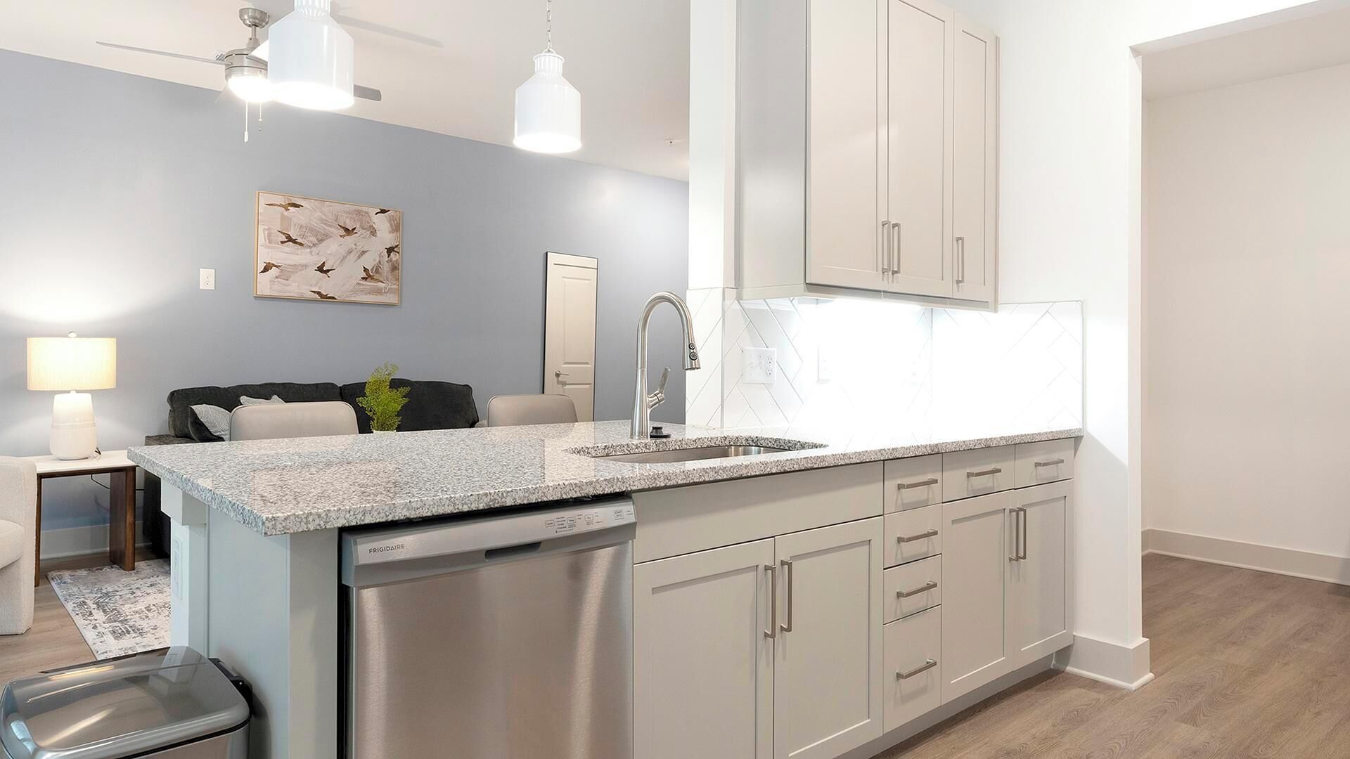 A modern kitchen with a built-in dishwasher, stainless steel cabinets, and a granite countertop.