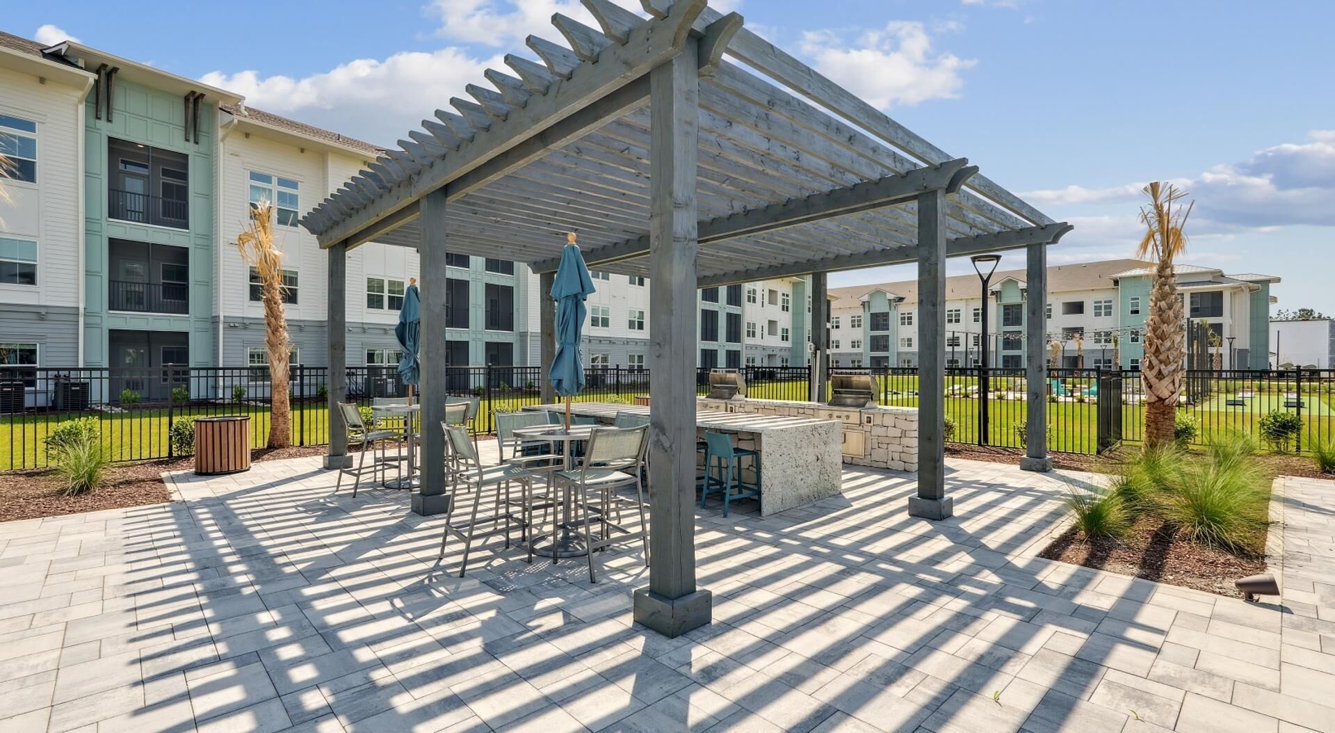 An outdoor patio area with a pergola, seating, and a barbecue station.