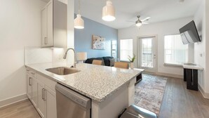 A modern kitchen with granite countertops, stainless steel appliances, and pendant lighting.