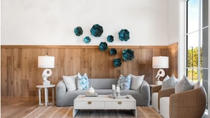 Ein modernes Wohnzimmer mit einem grauen Sofa, einem weißen Couchtisch und einem großen Fenster.