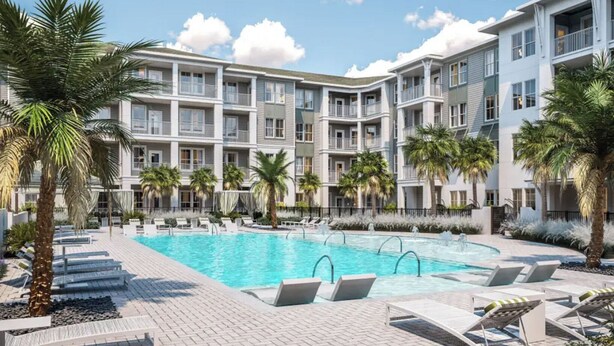 A hotel with a central swimming pool surrounded by lounge chairs and palm trees. - Landing | Beautiful 2BD, Pool (Palm Coast)