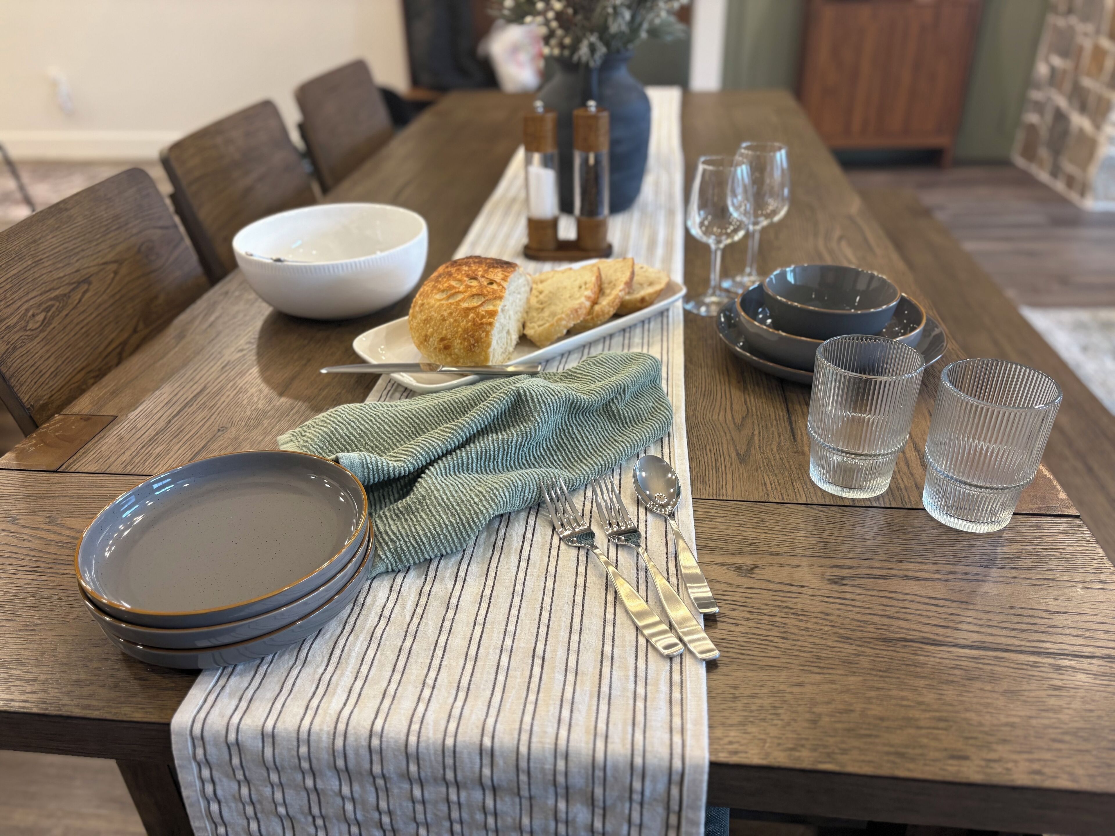 Una mesa de comedor lista con platos, tazones, vasos y cubiertos.
