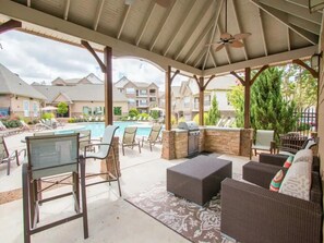 Un'area esterna riparata con piscina, poltrona relax e angolo barbecue.