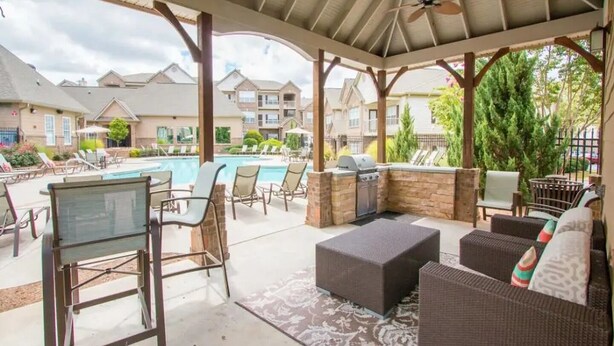 Un espace extérieur abrité comprenant une piscine, des chaises longues et un coin barbecue.