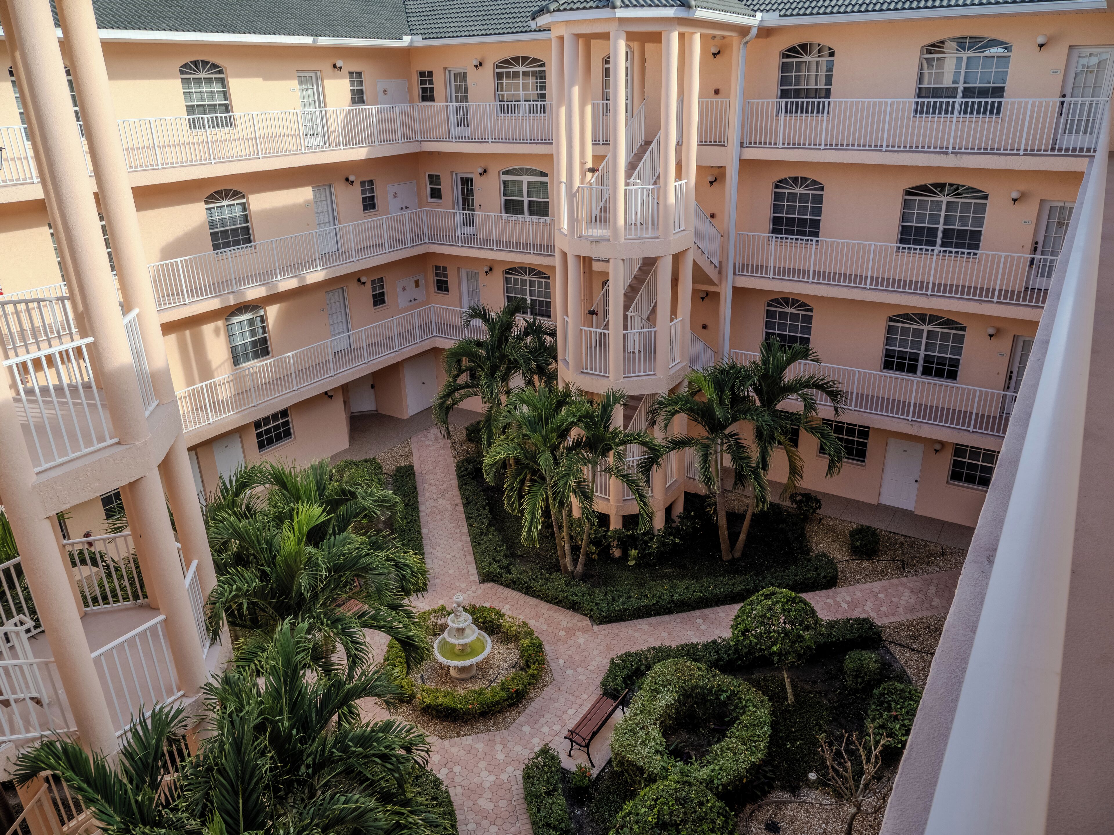 Un edificio a più piani con balconi, un cortile centrale con una fontana e palme.