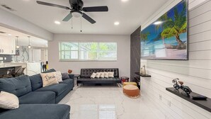 Uma sala de estar moderna com um sofá, uma mesa de centro e uma TV fixada na parede.