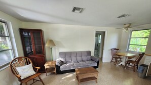 A living room with a grey sofa, wooden chairs, a small table, and a cabinet. - Paradise in the heart of Old Englewood Village (Englewood)
