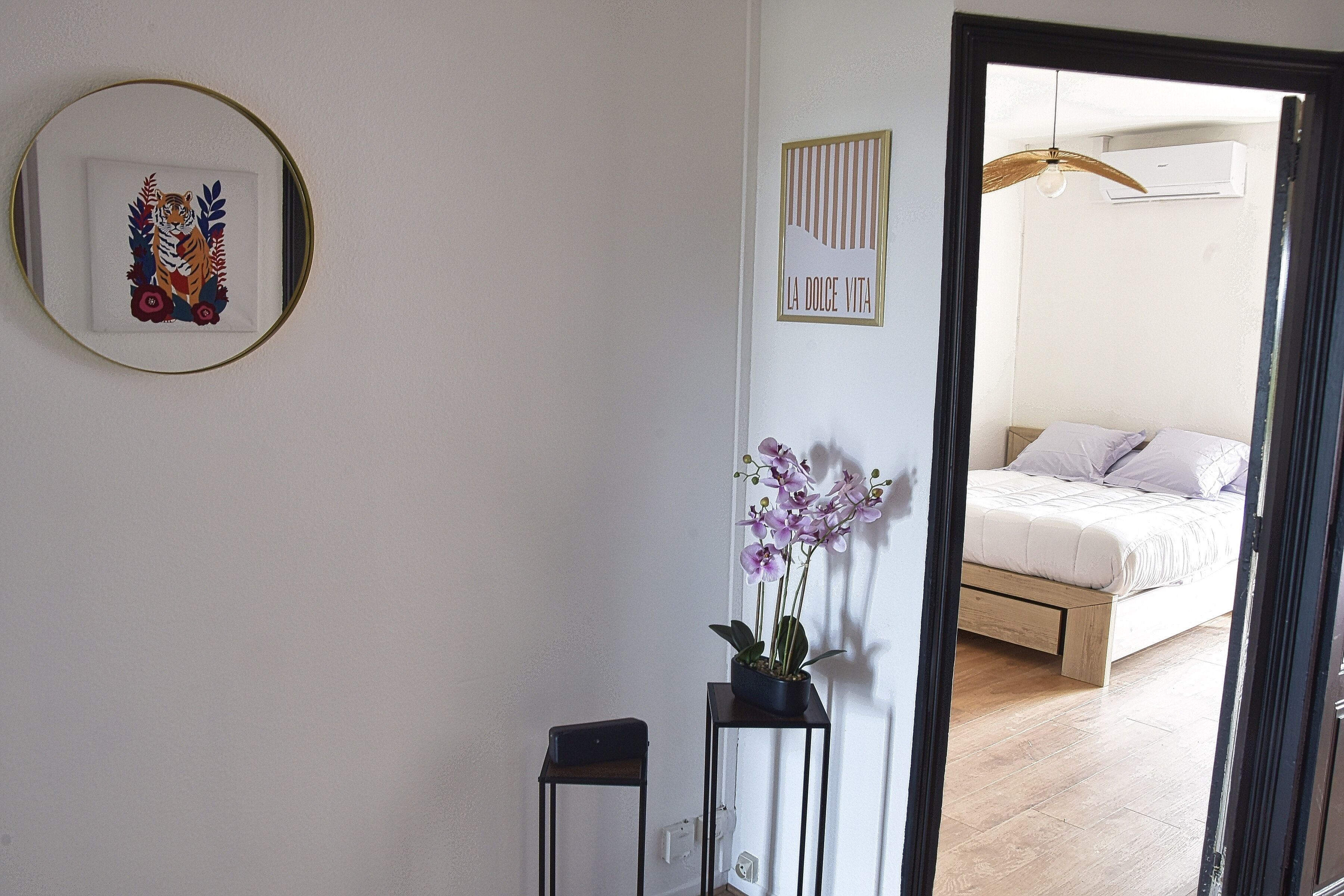 Un dormitorio con una cama, una orquídea en maceta y un cuadro en la pared.