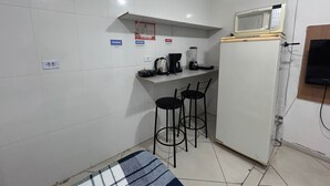 A small kitchenette with a microwave, coffee maker, and two bar stools. There are hygiene signs on the wall and a power outlet. - Studio próximo Santana SP (São Paulo)