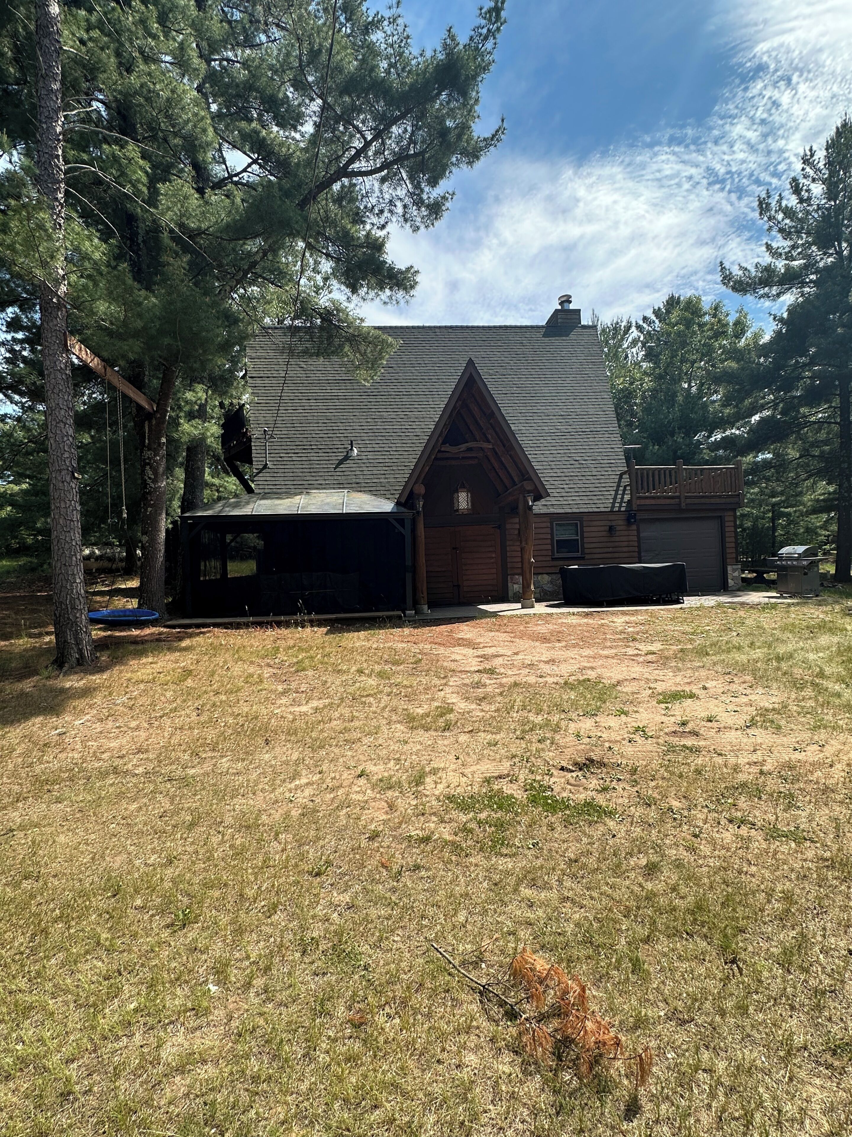 Une cabane avec un toit en pente, un garage et une véranda couverte.