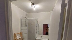 A bathroom with a toilet, a shower, a sink, and a mirror. - Studio ideally located (Sens)