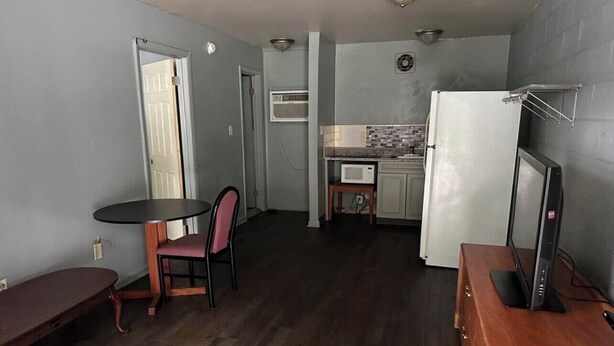 A compact living space with a dining area, kitchenette, and a flat-screen TV on a wooden dresser.