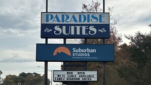 A sign for Paradise Suites, indicating WiFi, cable availability, and 1 and 2 bedroom suites.