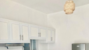 A modern kitchen with white cabinets, a black countertop, stainless steel appliances, and a dining area with a table and chairs. - LA CASITA DE CHEPE - Iconic apartment in Gaspar Hernandez (Gaspar Hernández)