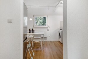 Une cuisine compacte comprenant une table à manger, des chaises, une fenêtre avec vue et un lave-linge.