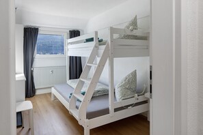 Et soveværelse med køjeseng, et vindue, en radiator og et skrivebord.
