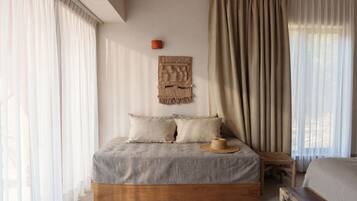 Een slaapkamer met een bed, een hoed, een wandkleed en een houten bankje.