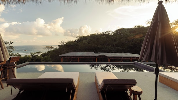 A poolside area with lounge chairs and a wooden deck overlooking the ocean.
