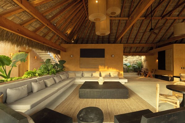 A spacious living area with a large sectional sofa, a coffee table, and a dining table with chairs. - Casa Yute Boutique Hotel Playa Aragon (Santa María Tonameca)