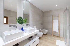 Une salle de bain moderne avec deux lavabos, des toilettes et un espace douche.