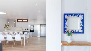 A modern kitchen with white cabinetry, a dining area with white chairs, and a blue decorative mirror on the wall. - -Nuevo Anuncio- Bádminton Villa & Sea Views (Finestrat)