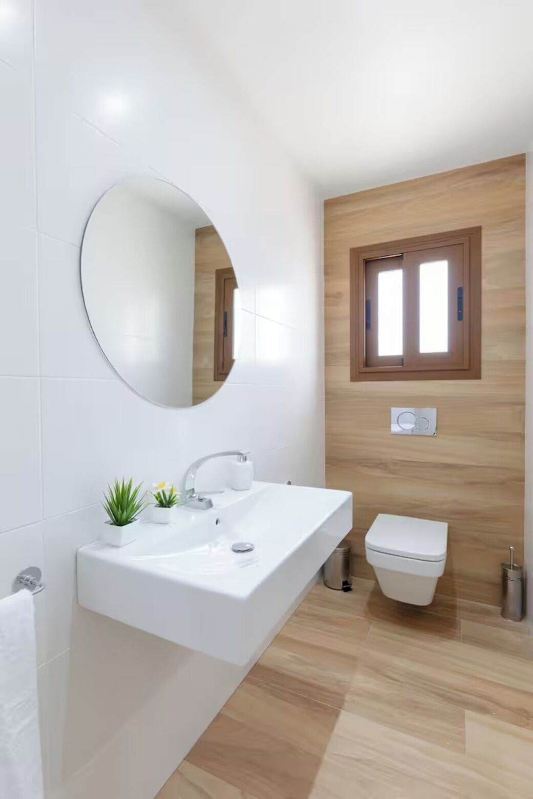 Une salle de bain moderne avec un lavabo blanc, un miroir et des toilettes.