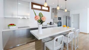 A modern kitchen with a central island, stainless steel cabinets, and pendant lighting. - -Nuevo Anuncio- Bádminton Villa & Sea Views (Finestrat)