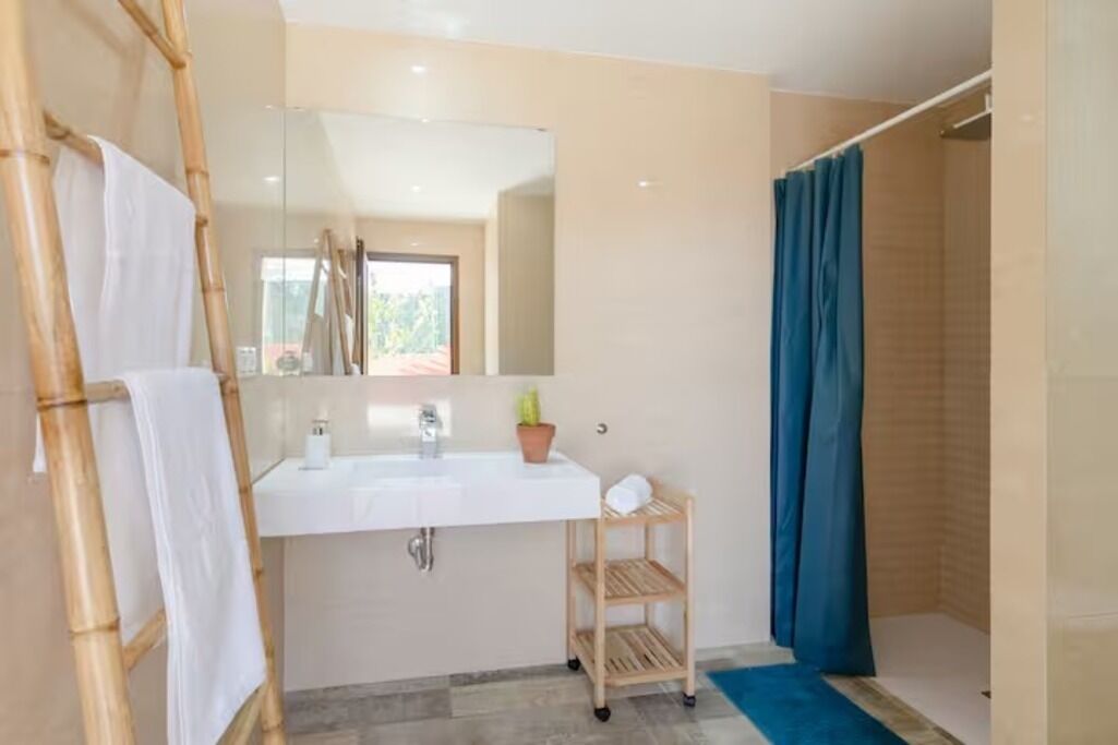Une salle de bain avec un lavabo blanc, un miroir et une douche avec un rideau bleu.