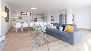 A modern living room with a grey sofa, a glass coffee table, and a dining area with white chairs and a white table. - -Nuevo Anuncio- Bádminton Villa & Sea Views (Finestrat)